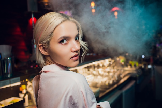 Retrato de una niña en un bar nocturno, detrás del mostrador.