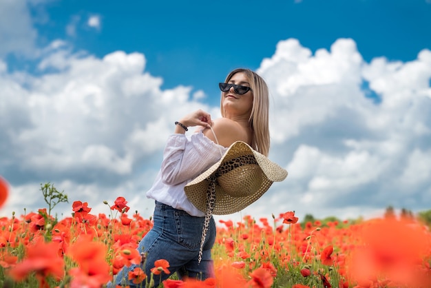 Retrato de niña de belleza y moda en campo de amapolas. Hora de verano