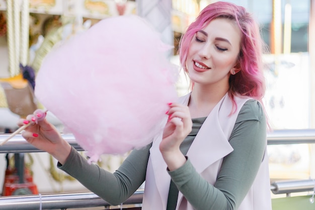 Retrato de niña bonita con cabello rosado con corte de pelo corto posando en el parque de atracciones