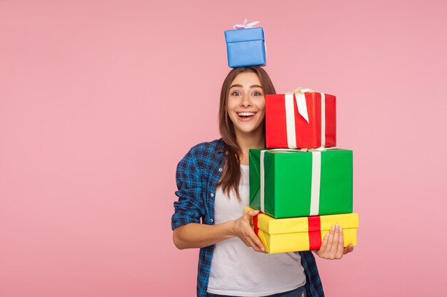 Retrato de niña bonita mirando a la cámara con expresión de sincera felicidad infantil y sosteniendo muchos regalos una caja en la cabeza disfrutando de regalos de cumpleaños vacaciones de navidad foto de estudio aislado