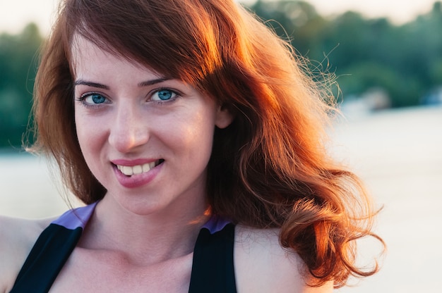 Retrato de niña bonita realmente sonriente, en verano naturaleza borrosa