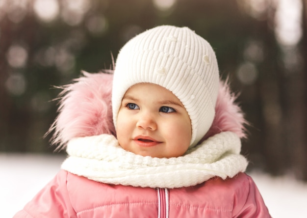Retrato de una niña bonita con un sombrero blanco en invierno en la naturaleza