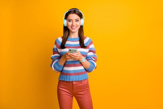 Retrato de niña bonita sosteniendo en manos teléfono escuchar música auriculares