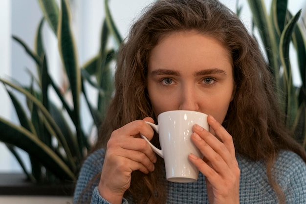 Retrato de niña con cabello castaño grueso con taza de té Chica con belleza natural bebe café de taza blanca