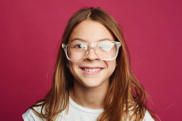 Retrato de niña de cabello castaño sobre fondo rosa