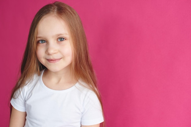 Retrato de niña de cabello castaño sobre fondo rosa