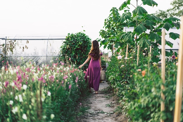 Retrato de niña con cabello largo con una canasta de flores. Camina por el jardín de flores. Niña y flores. Florística.