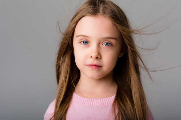 Retrato de una niña con cabello largo en un espacio claro