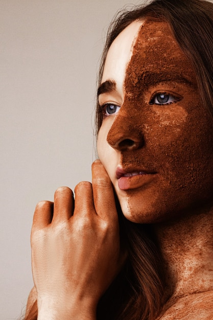 Foto retrato de una niña con cacao en polvo en el rostro de cerca. concepto de moda y belleza. chica toca su mejilla.