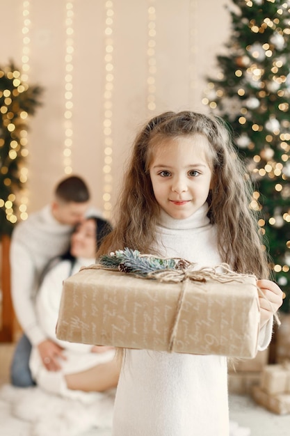 Retrato de una niña con caja de regalo y sus padres detrás