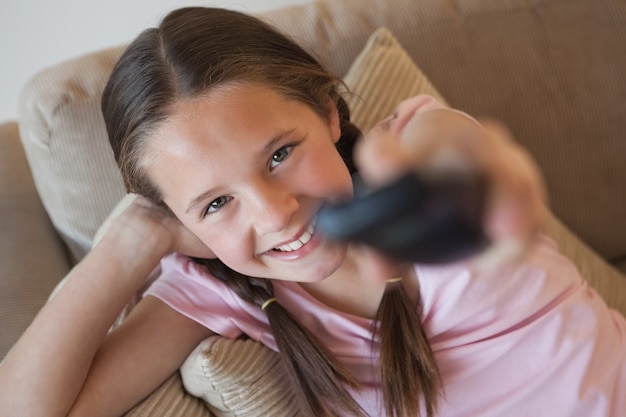 Retrato de una niña cambiando los canales en la sala de estar