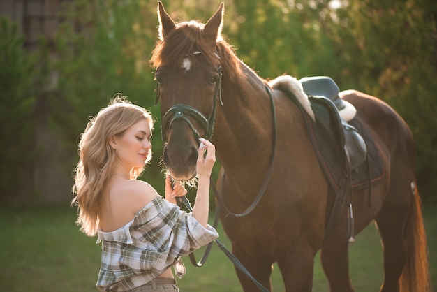 Retrato de niña camisa inplaid con caballo negro en la granja de caballos.