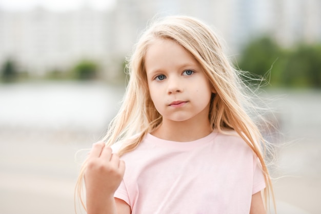 Retrato de una niña con una camisa rosa en la calle.