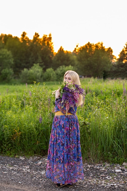 Retrato de una niña en un campo floreciente bajo el sol al atardecer