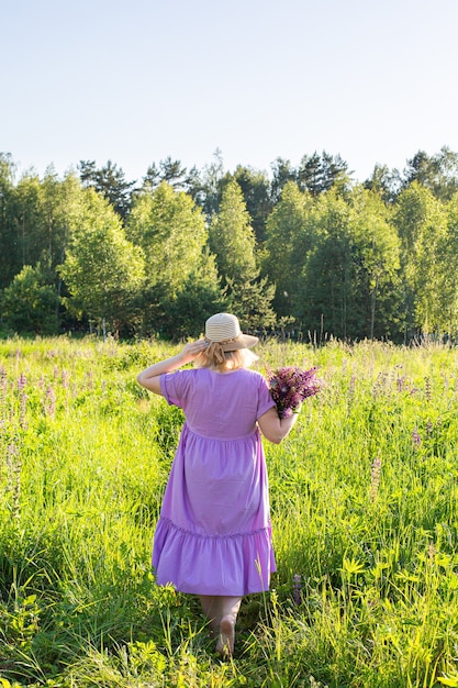 Retrato de una niña en un campo floreciente bajo el sol al atardecer