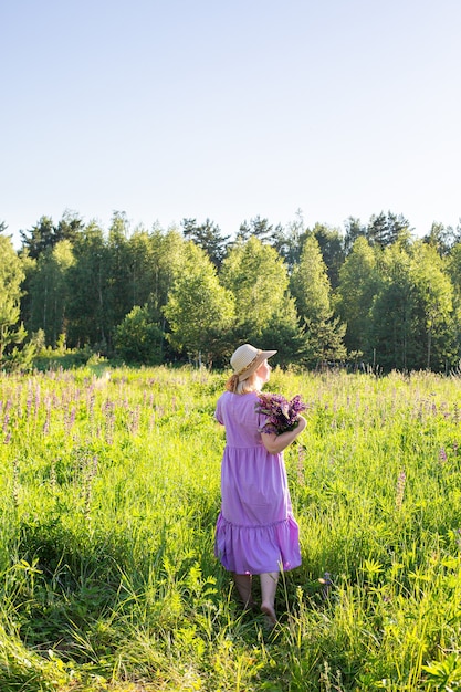 Retrato de una niña en un campo floreciente bajo el sol al atardecer