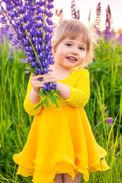 Retrato de una niña en un campo floreciente bajo el sol al atardecer