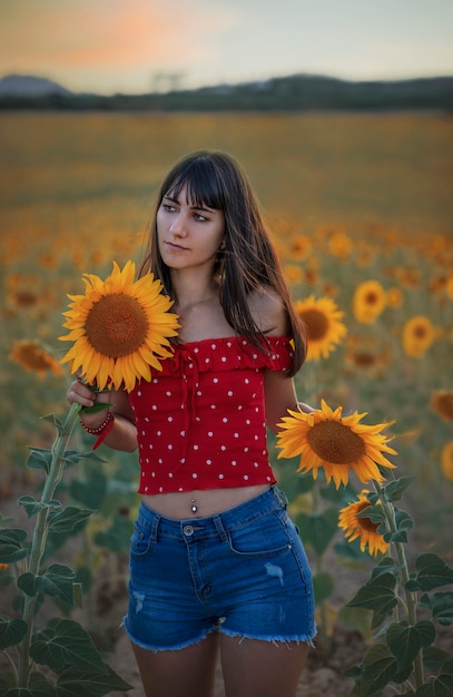 Retrato de una niña en un campo de girasoles durante la puesta de sol.