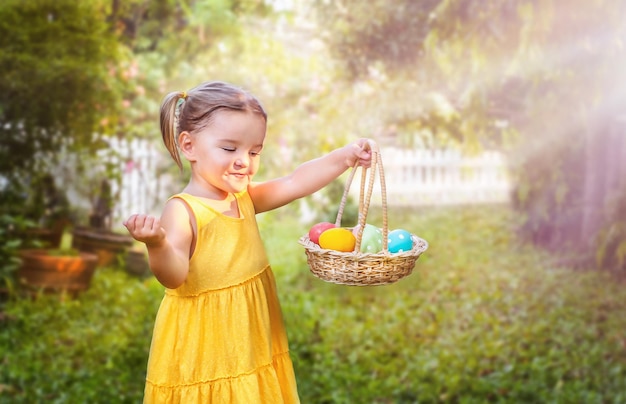 Retrato de una niña con una canasta de Pascua con huevos en el patio trasero