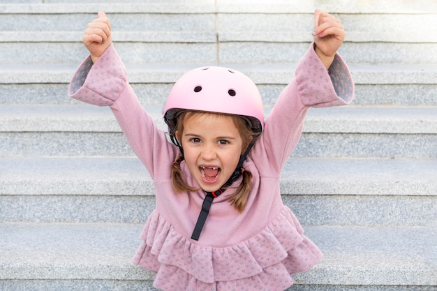 Foto retrato niña con casco levantando sus manos