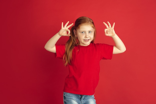 Retrato de niña caucásica aislado en la pared roja