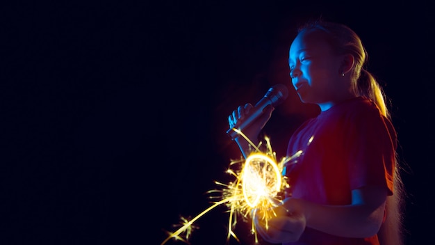 Retrato de niña caucásica aislado sobre fondo oscuro de estudio en luz de neón