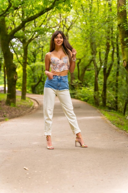 Retrato de una niña caucásica en un camino en un parque de la ciudad posado a la moda en la naturaleza