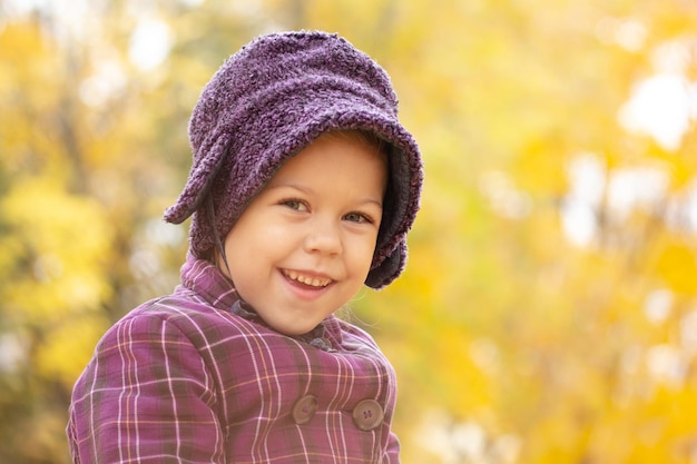 Retrato de una niña caucásica de cinco años mirando a la cámara en el parque de otoño con luz amarilla