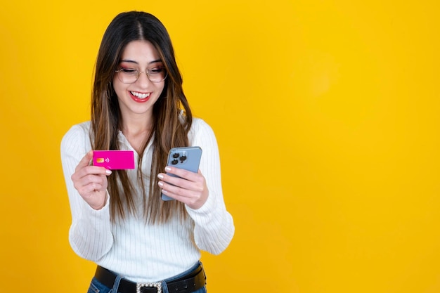 Retrato de niña caucásica feliz con tarjeta de crédito y teléfono móvil Concepto de compras en línea