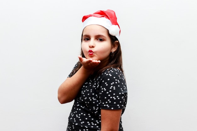 Retrato de niña caucásica con sombrero de navidad, fondo blanco.