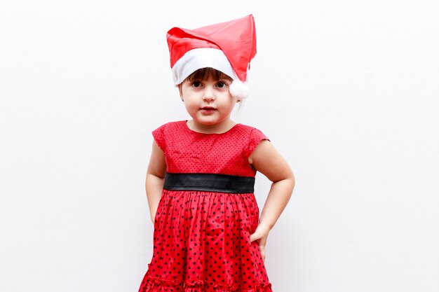 Retrato de niña caucásica con sombrero de navidad, fondo blanco.