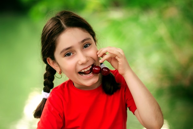 Retrato de una niña con una cereza roja