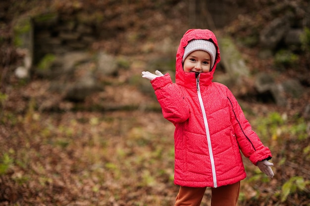 Retrato de niña en chaqueta con capucha rosa en el bosque de otoño