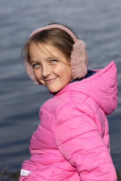 Retrato de una niña con una chaqueta rosa y auriculares de piel.