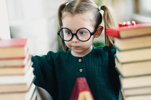 Retrato de niña científico lindo con gafas y libros. Enfoque suave selectivo