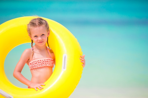 Retrato de niña con círculo de goma inflable en vacaciones en la playa