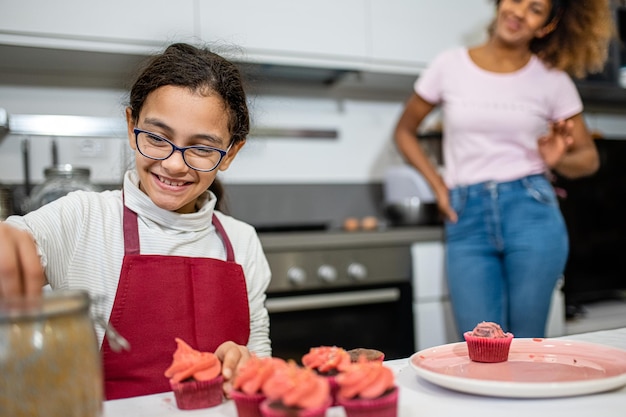 Foto retrato de una niña cocinando madre e hija cocinando pasteles en la cocina momento genuino de unión entre padres y niños