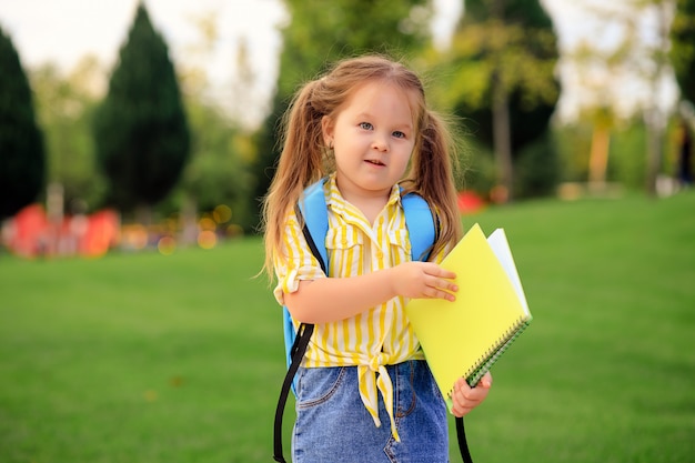 Retrato de una niña colegiala linda feliz en el parque