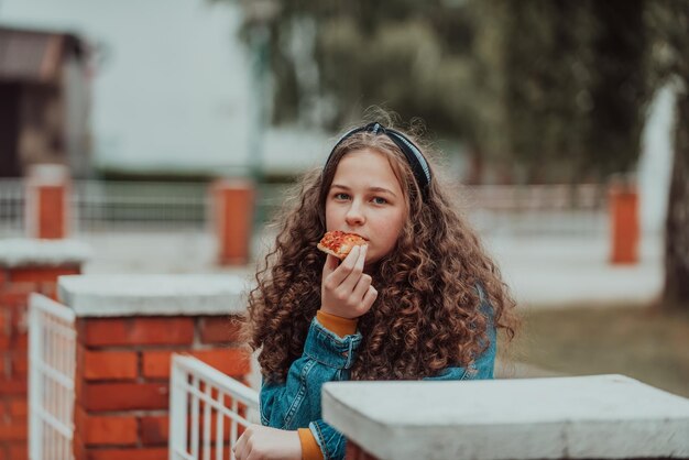 Foto retrato de una niña comiendo pizza en un almuerzo en la escuela durante la apertura gradual después del cierre de la pandemia enfoque selectivo foto de alta calidad