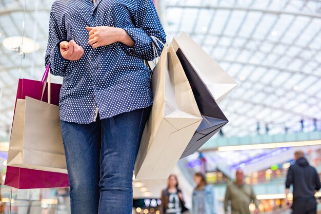 Retrato de niña de compras de moda. Mujer de belleza, con, bolsas de compras, en, centro comercial