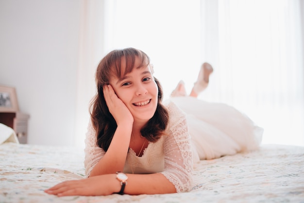 Retrato de una niña de comunión en su cama mirando a la cámara sonriendo