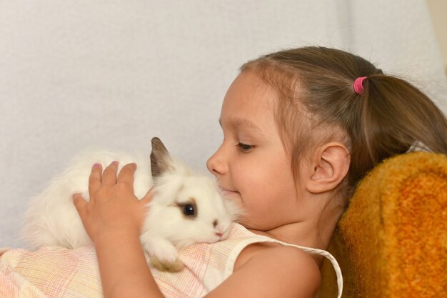 Retrato de una niña con un conejo en casa