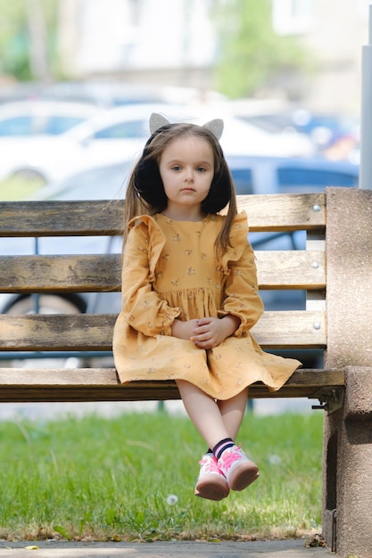 Retrato de una niña de cuatro años sentada en un banco del parque