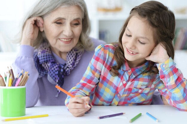 Retrato de niña dibujando con su abuela en casa