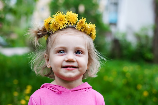 Retrato de niña de dos años con vestido rosa y corona en la cabeza.