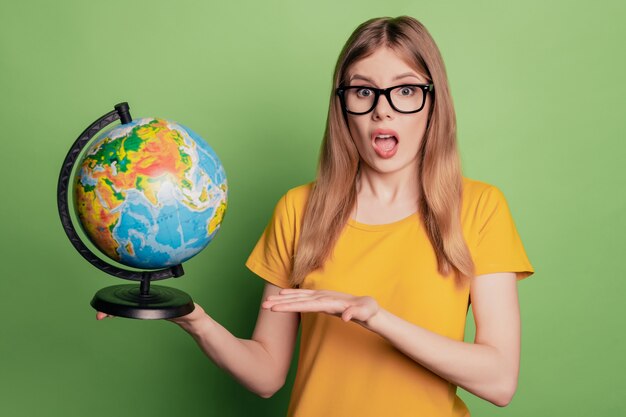 Retrato de niña emocionada maestra de geografía dama demostrar globo esfera usar gafas camiseta amarilla