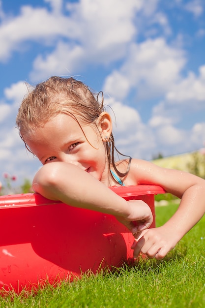 Retrato de niña encantadora y sonriente disfrutando de sus vacaciones en la piscina al aire libre