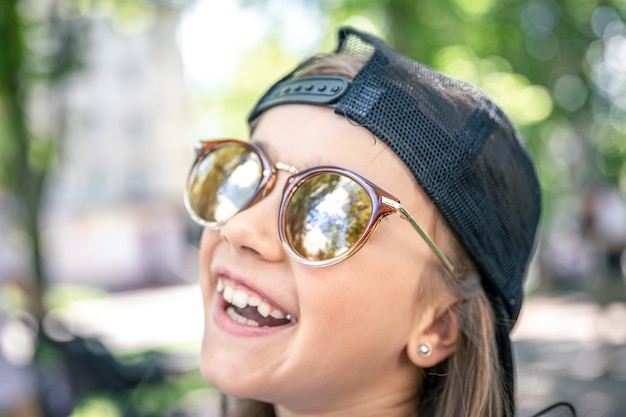 Retrato de una niña con estilo en gafas de sol al aire libre.