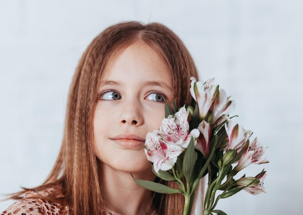 Retrato de una niña en el estudio Una niña se para y sostiene un ramo de flores en sus manos