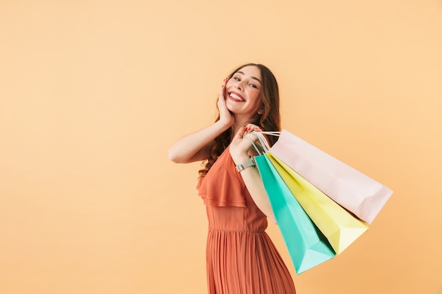 Retrato de una niña feliz de 20 años que lleva bolsas de papel de colores, estando aislado